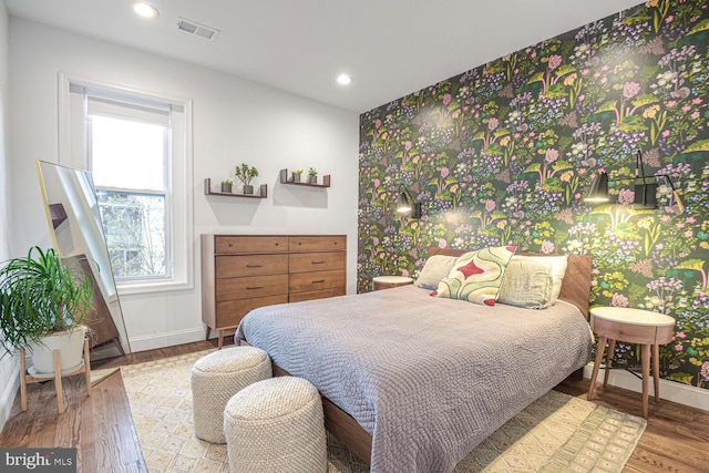 bedroom featuring baseboards, visible vents, wood finished floors, and recessed lighting