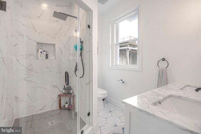 full bath featuring double vanity, a marble finish shower, toilet, and a sink