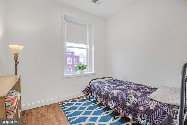 bedroom featuring visible vents, baseboards, and wood finished floors