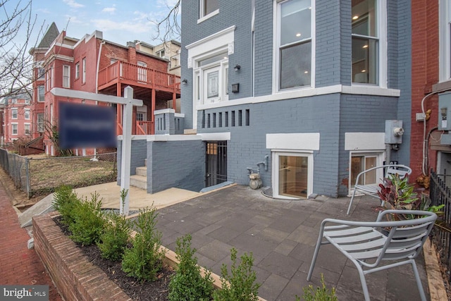 back of property with brick siding, a patio area, and fence