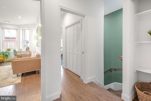 hall featuring recessed lighting, baseboards, wood finished floors, and an upstairs landing