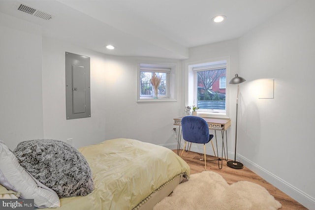 bedroom featuring electric panel, visible vents, baseboards, and wood finished floors