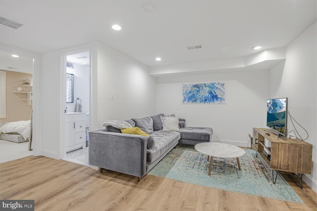 living area with light wood-style flooring, visible vents, and recessed lighting