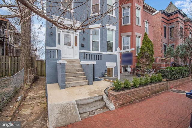 view of property featuring brick siding and fence