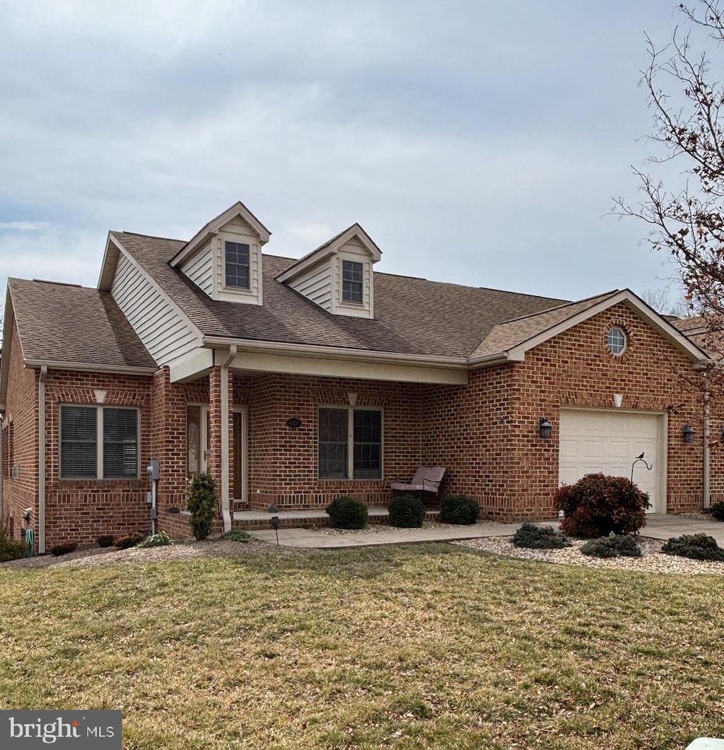 view of front of home with an attached garage, roof with shingles, a front lawn, and brick siding