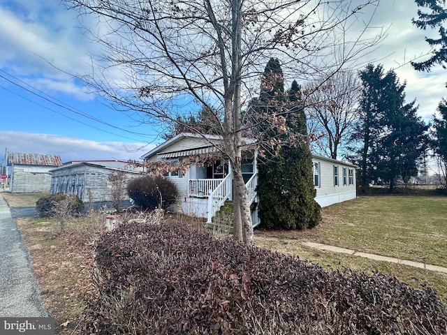 view of side of property with covered porch and a lawn