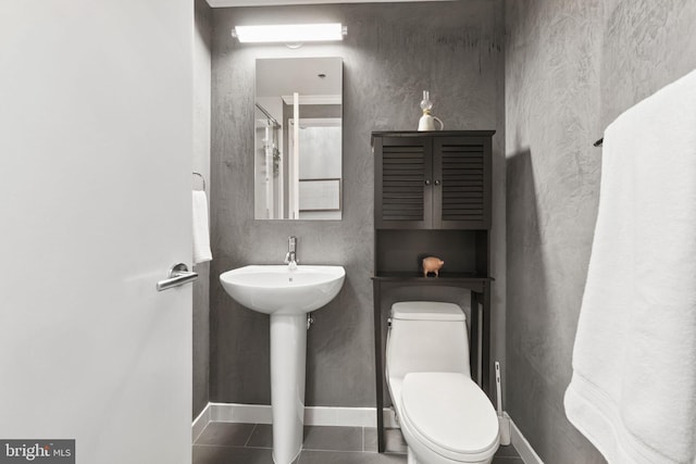 bathroom featuring toilet, baseboards, a sink, and tile patterned floors