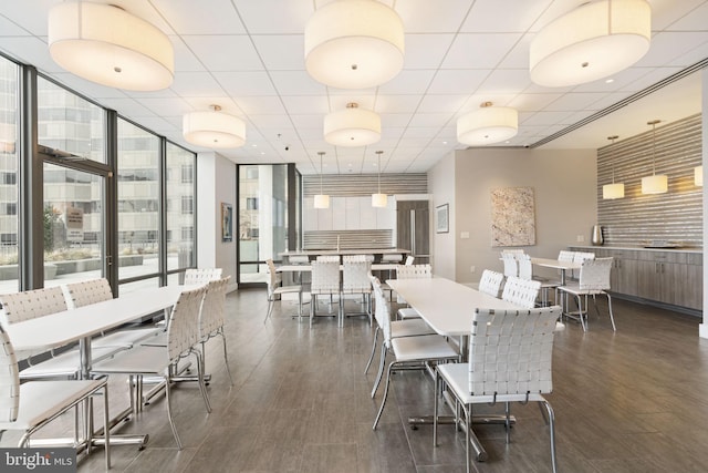 dining area featuring expansive windows, a drop ceiling, and dark wood finished floors