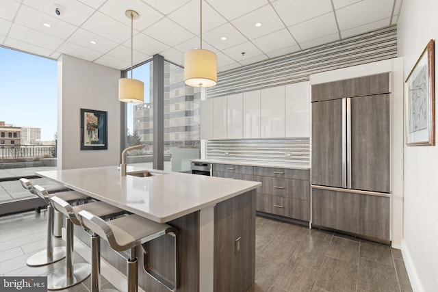 kitchen featuring a sink, paneled fridge, modern cabinets, and light countertops