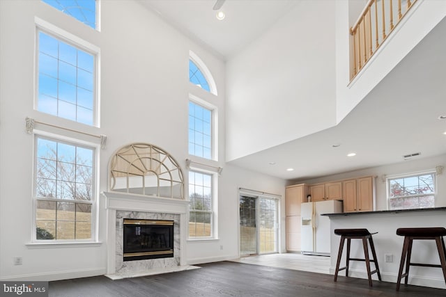 interior space featuring white fridge with ice dispenser, a healthy amount of sunlight, light brown cabinets, and dark wood finished floors