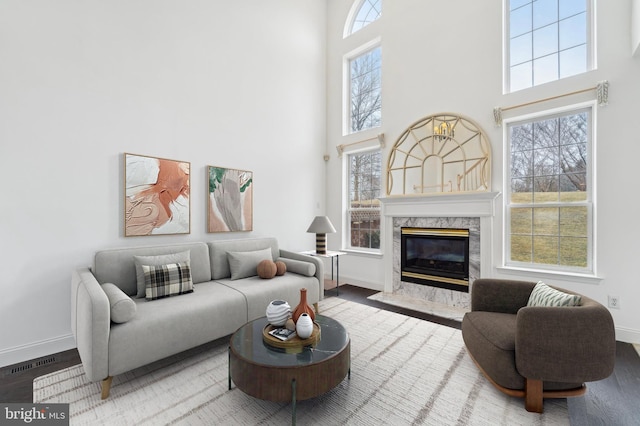 living room featuring a high ceiling, a fireplace, wood finished floors, and baseboards