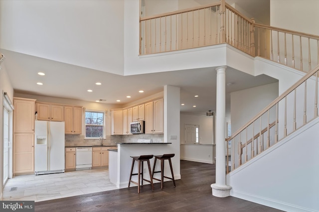 kitchen featuring dark countertops, white appliances, light wood-style flooring, and a towering ceiling