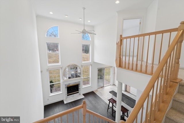 interior space featuring a fireplace, recessed lighting, a high ceiling, ceiling fan, and wood finished floors