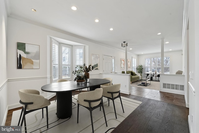 dining room featuring a healthy amount of sunlight, decorative columns, crown molding, and wood finished floors