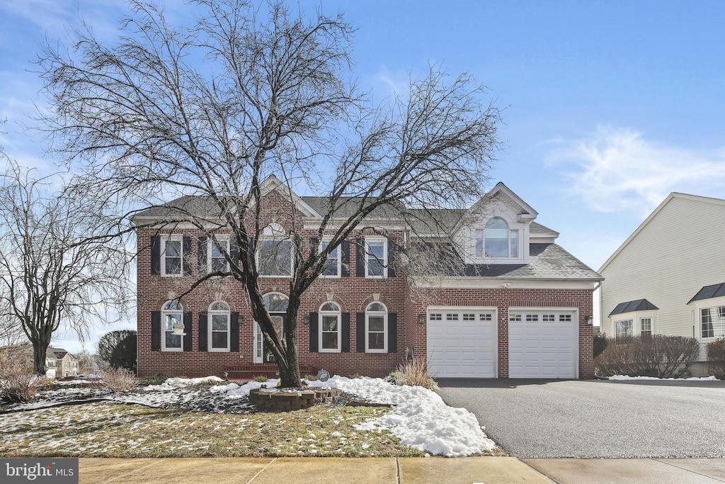 view of front facade with driveway, an attached garage, and brick siding