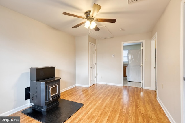 living room featuring ceiling fan, light hardwood / wood-style flooring, and a wood stove