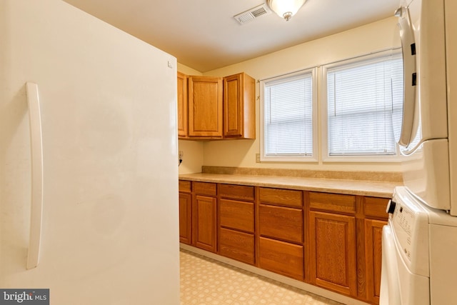 clothes washing area featuring cabinets and stacked washer and clothes dryer