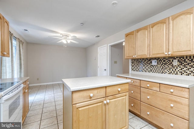 kitchen with light tile patterned flooring, ceiling fan, a kitchen island, white range with electric cooktop, and decorative backsplash