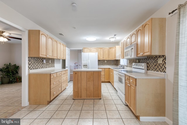 kitchen with white appliances, light brown cabinetry, a center island, and light tile patterned floors