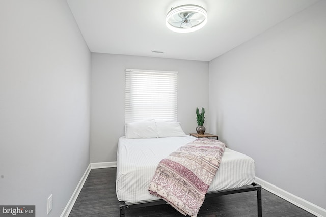 bedroom with dark wood-style floors, visible vents, and baseboards