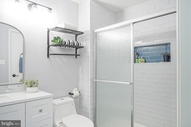 bathroom featuring toilet, a tile shower, and vanity