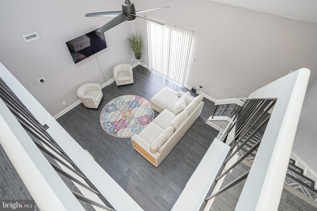 living room with ceiling fan, dark wood-type flooring, visible vents, and baseboards