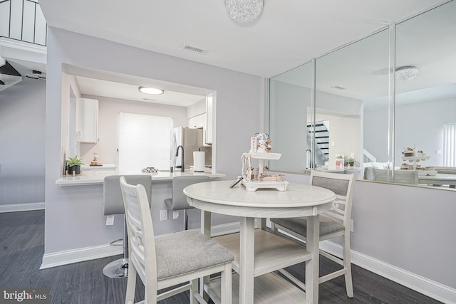 dining space featuring dark wood-style floors, stairway, visible vents, and baseboards