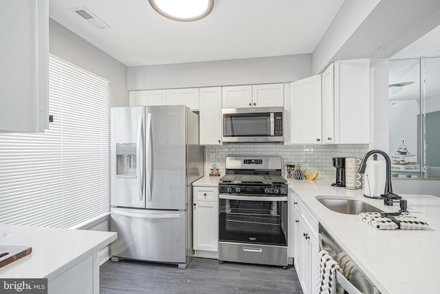 kitchen featuring appliances with stainless steel finishes, light countertops, a sink, and white cabinetry