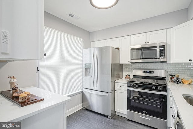 kitchen with light countertops, visible vents, decorative backsplash, appliances with stainless steel finishes, and white cabinets