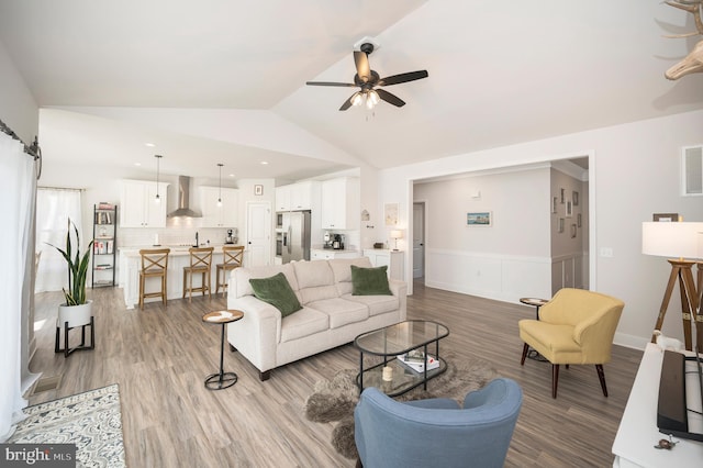 living room featuring hardwood / wood-style flooring, ceiling fan, and vaulted ceiling