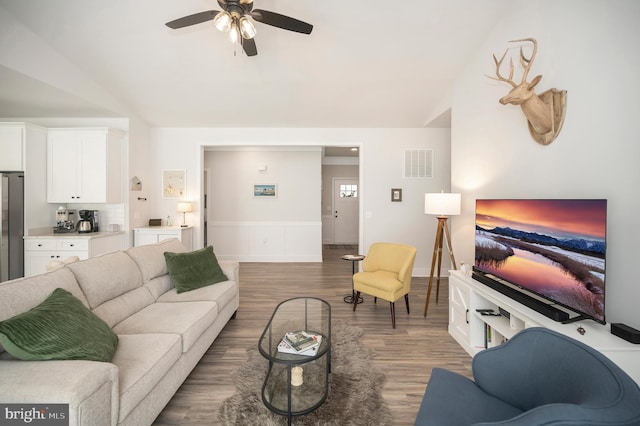 living room with dark wood-type flooring, ceiling fan, and vaulted ceiling