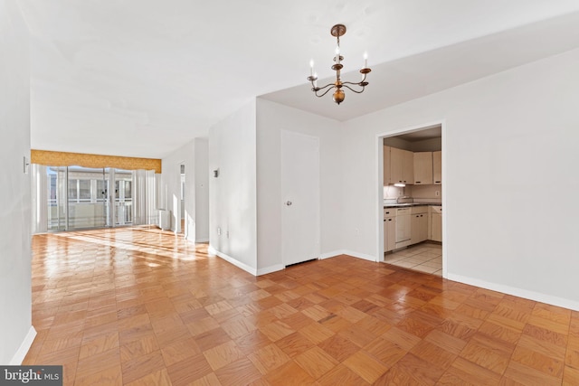 unfurnished room with a notable chandelier and light parquet floors