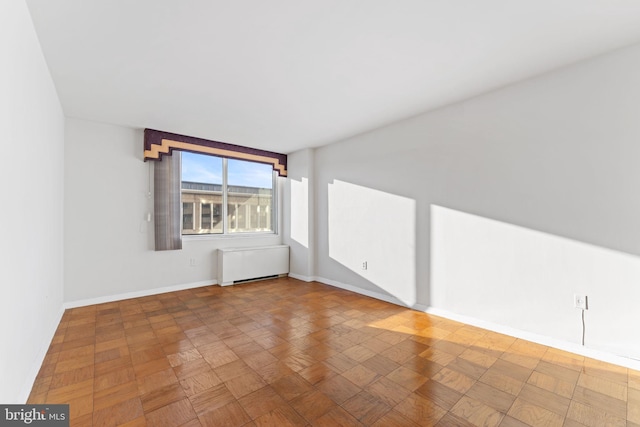 spare room featuring radiator and parquet floors