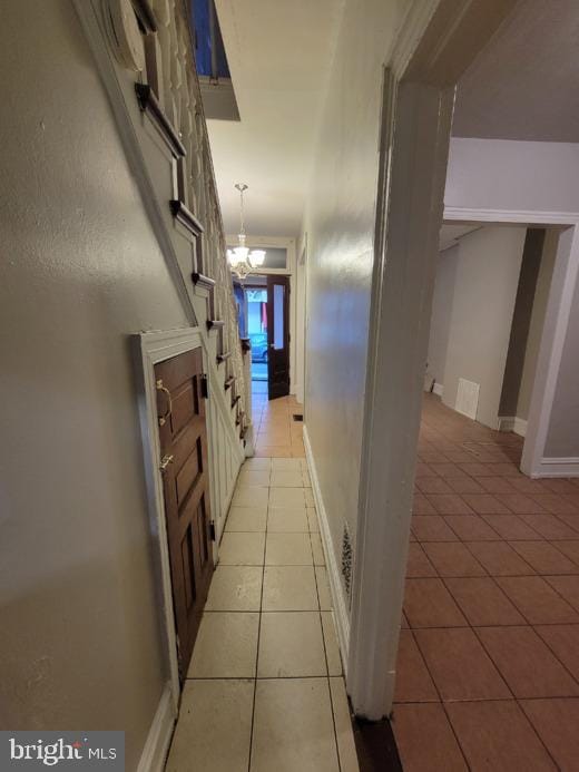 hall featuring light tile patterned flooring and a notable chandelier