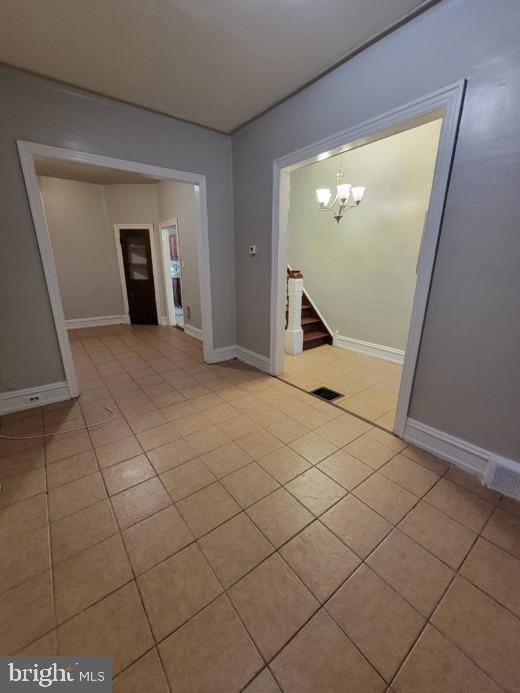 tiled empty room with an inviting chandelier