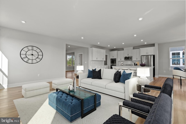 living room featuring a healthy amount of sunlight, sink, and light hardwood / wood-style flooring