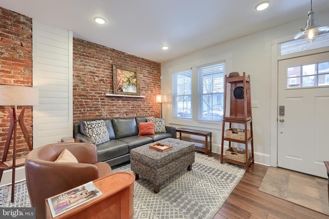 living room featuring brick wall, wood-type flooring, and plenty of natural light