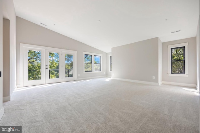 unfurnished living room featuring light colored carpet, high vaulted ceiling, and french doors