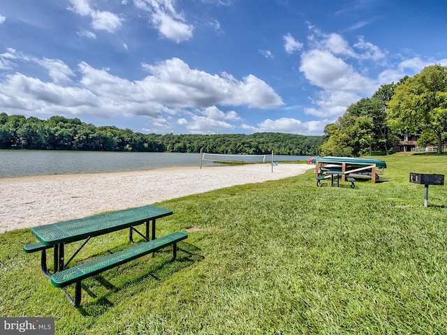 surrounding community with a yard, volleyball court, and a water view