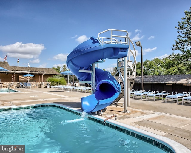 view of pool featuring a water slide and a patio area