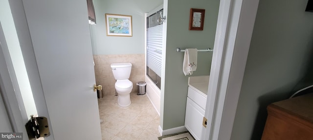 full bathroom featuring wainscoting, toilet, tile patterned floors, vanity, and tile walls