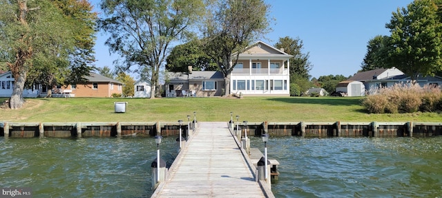 dock area featuring a water view, a balcony, and a lawn