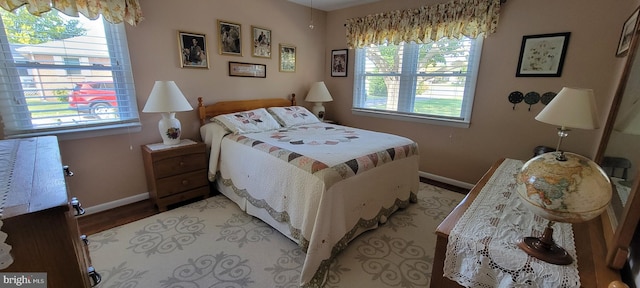 bedroom featuring multiple windows, light wood-type flooring, and baseboards