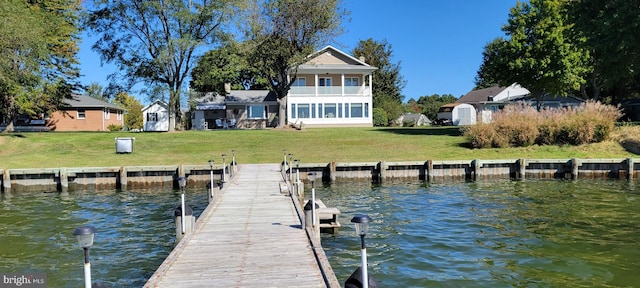 view of dock with a water view, a balcony, and a yard