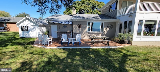 back of property featuring a lawn, a balcony, a chimney, a patio area, and brick siding