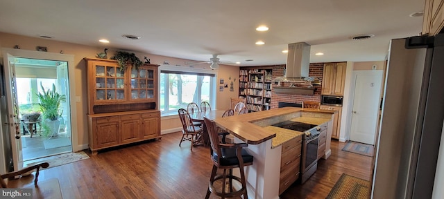 kitchen with stainless steel appliances, dark wood-type flooring, a kitchen bar, and extractor fan