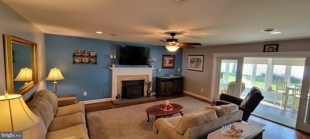 living room featuring visible vents, a fireplace, baseboards, and wood finished floors