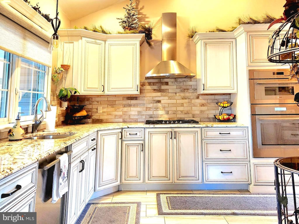 kitchen with extractor fan, stainless steel appliances, a sink, cream cabinetry, and backsplash