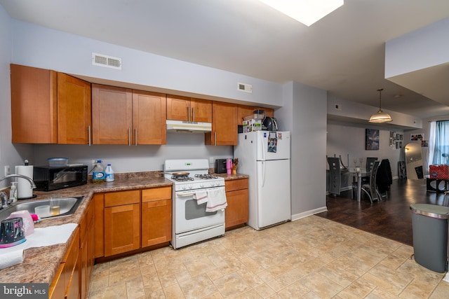 kitchen with sink, white appliances, and hanging light fixtures