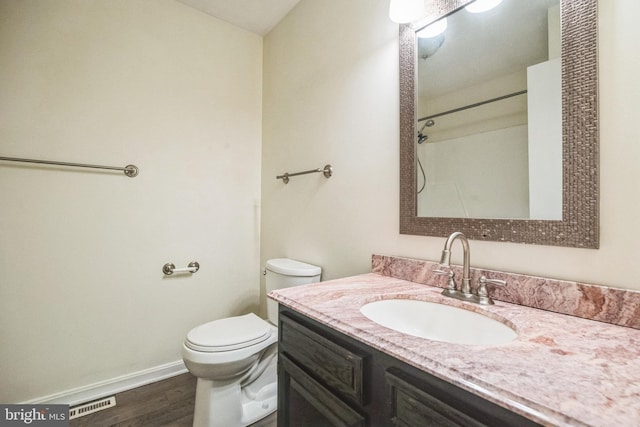 bathroom featuring visible vents, toilet, vanity, wood finished floors, and baseboards